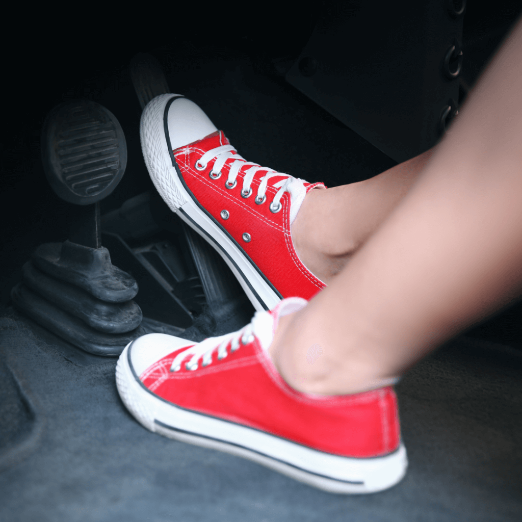Noisy Brakes? Common Causes and How to Fix Them 8 Person wearing red sneakers pressing a car brake pedal