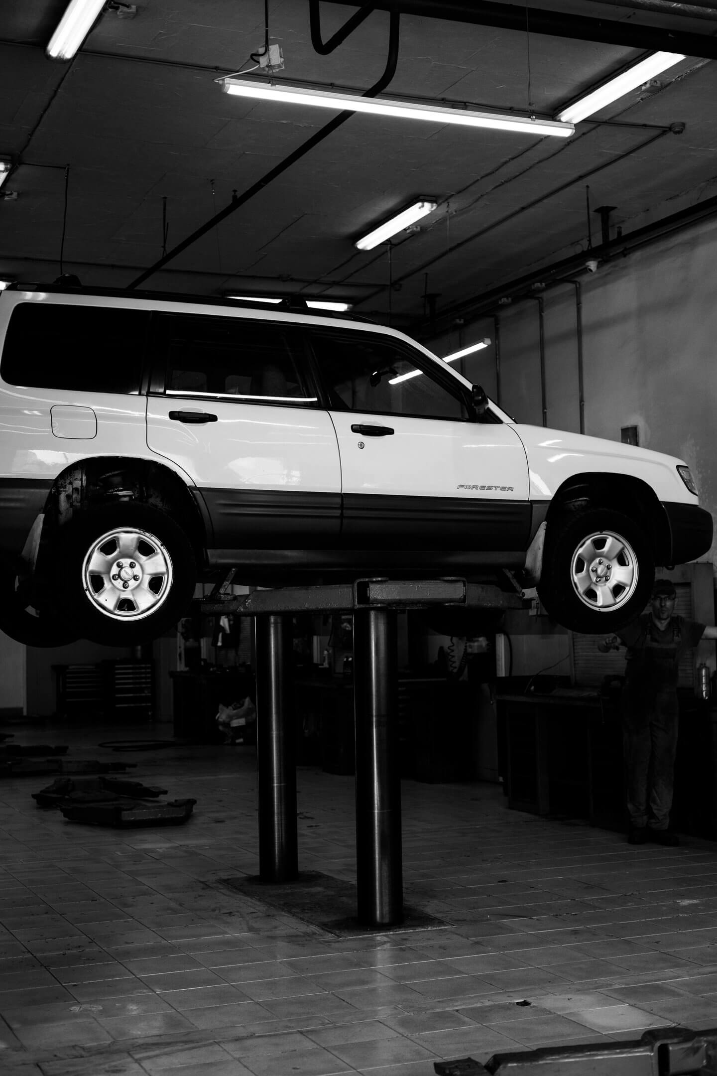 Vehicle on a hydraulic lift for suspension inspection at an auto repair shop in Newark, NJ.
