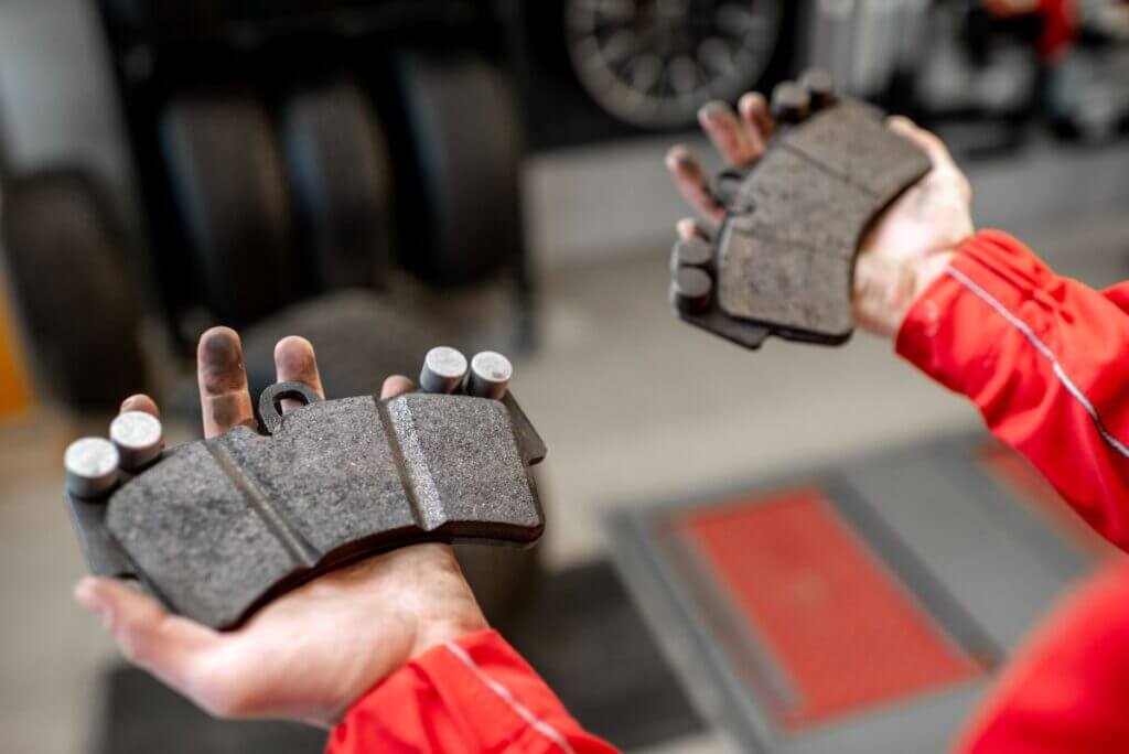 Mechanic showing new and worn brake pads side by side, illustrating the need for timely brake replacement at EPR Auto Clinic in Newark, NJ