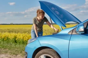 Woman checking car engine on the side of the road during spring maintenance.