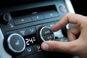 A hand adjusting the air conditioning controls on a car's dashboard, representing EPR Auto Clinic's expert AC repair services in Newark for a cool, comfortable ride