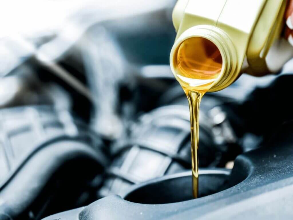 A technician pouring fresh, high-quality motor oil into a car's engine during a professional oil change service at EPR Auto Clinic in Newark