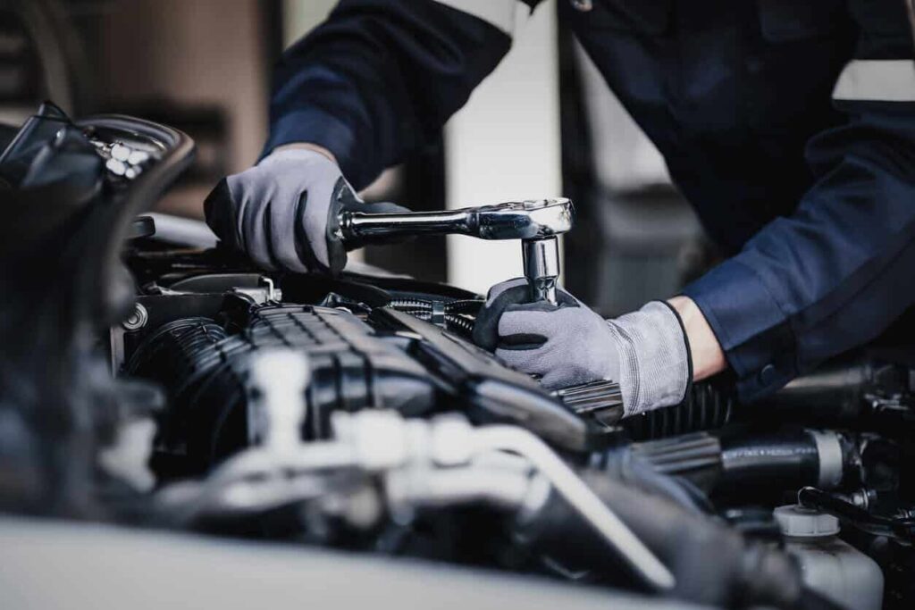 Mechanic using a socket wrench while working in a vehicle engine bay
